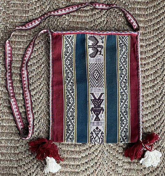 Traditional patterned bag with tassels on a textured surface