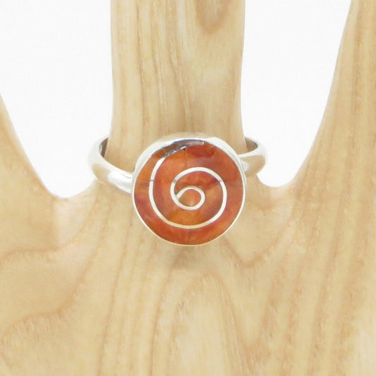 A silver-colored Incan patterns Pachamama spiral ring with a stone inlay, displayed on a wooden stand.